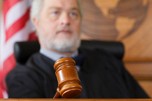 Judge seated in a courtroom with a gavel in the foreground during a legal hearing or sentencing proceeding