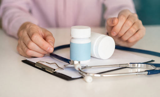 Prescription bottles placed beside a stethoscope and medical clipboard during a healthcare consultation.