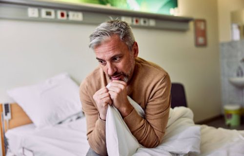 Man sitting in hospital bed clutching sheets, showing signs of fentanyl withdrawal symptoms during detox